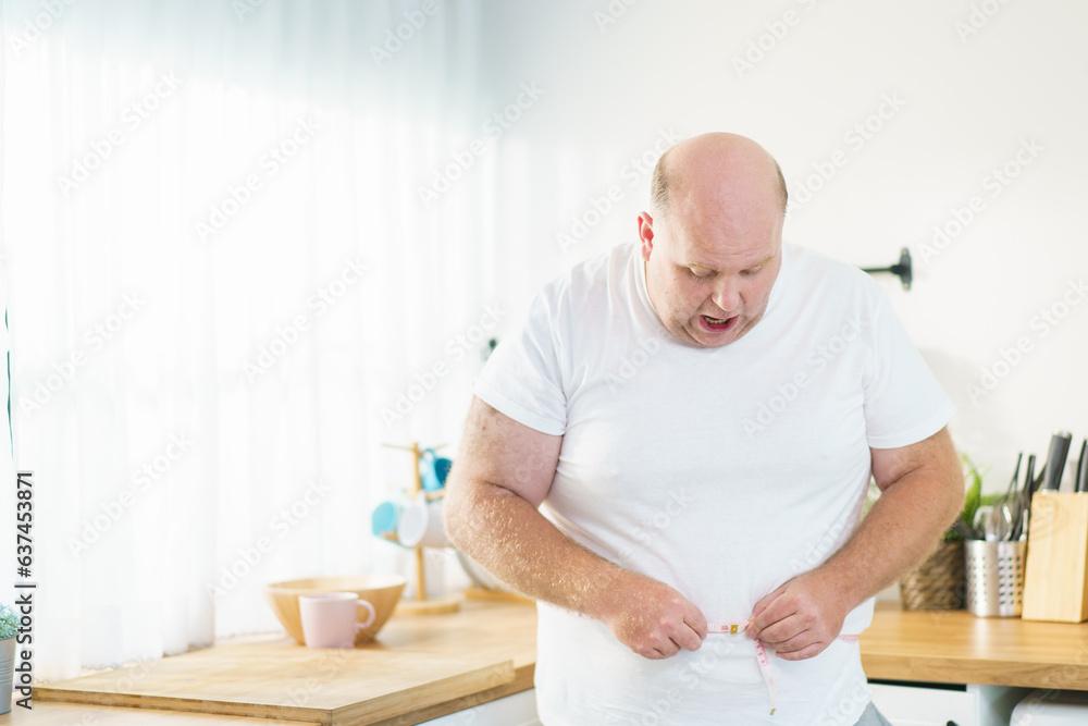 Very big oversize belly fat man using a measuring tape to measure his stomach, caucasian white man showing his excited face during using measuring tape on his belly. Very big oversize belly fat man using a measuring tape to measure his stomach, caucasian white man showing his excited face during using measuring tape on his belly.