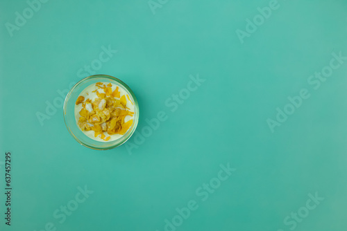 Morning Delights. Corn Flakes in a Glass Bowl on Green Background - Ready-to-Eat Cereal Captured in a Stunning Flat Lay with Copy Space.