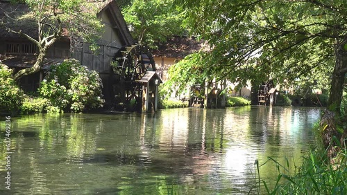 新緑の森の中を流れる小川に回る水車。環境音あり、固定撮影