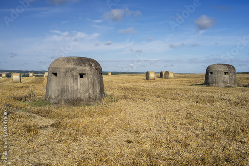 Poniemieckie kopuły powojennych bunkrów na polu po żniwach