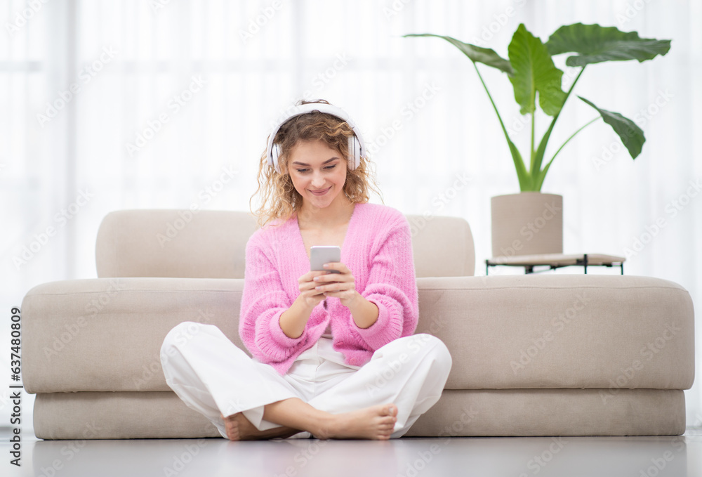 Young beautiful woman with smartphone and wireless headphones relaxing at home Young beautiful woman with smartphone and wireless headphones relaxing at home