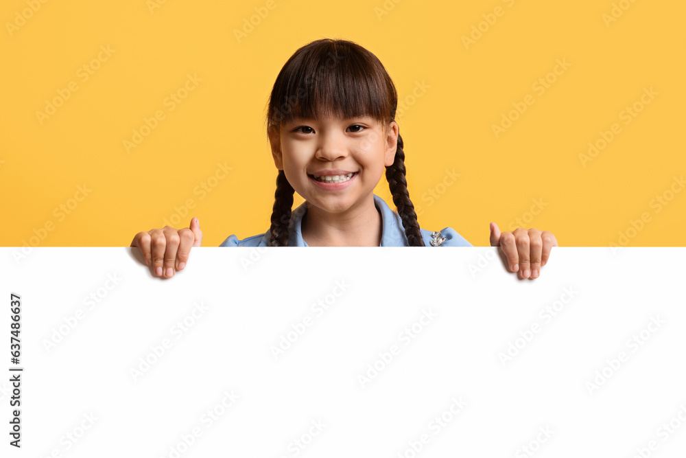 Cute little asian girl kid posing behind blank advertising board Cute little asian girl kid posing behind blank advertising board