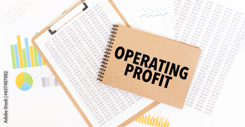 Text OPERATING PROFIT on brown paper notepad on the table with diagram. Business concept