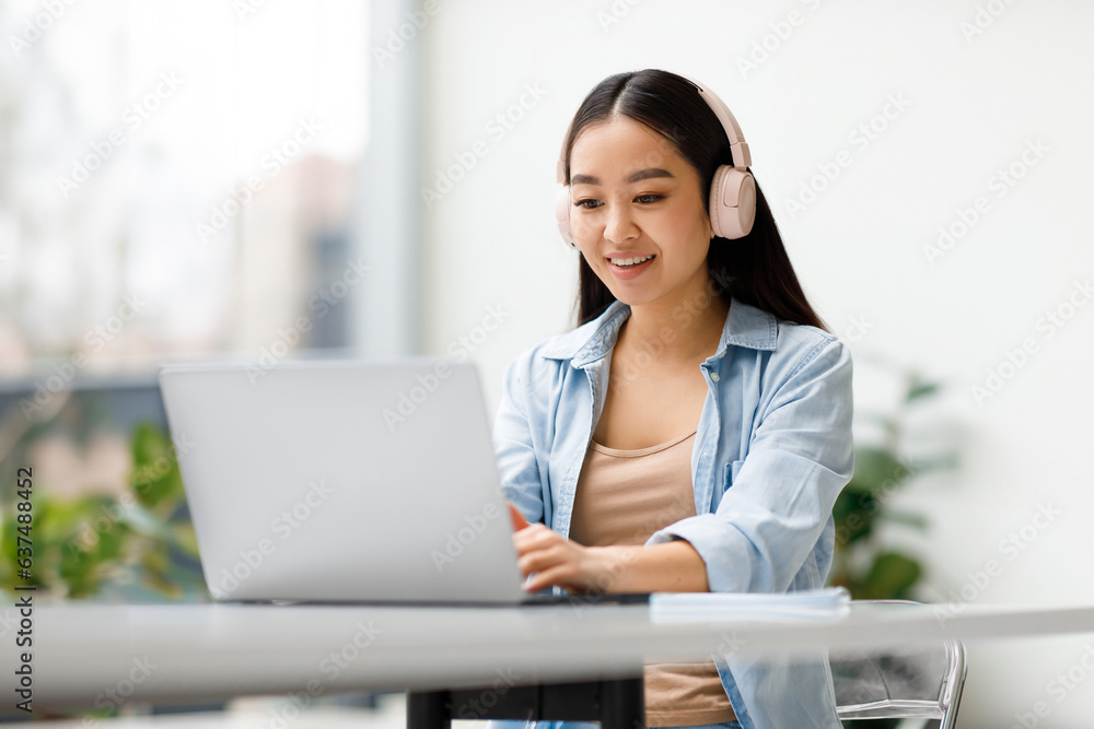 Online study. Cheerful asian lady using laptop, typing on keyboard, watching webinar, sitting in university audience Online study. Cheerful asian lady using laptop, typing on keyboard, watching webinar, sitting in university audience