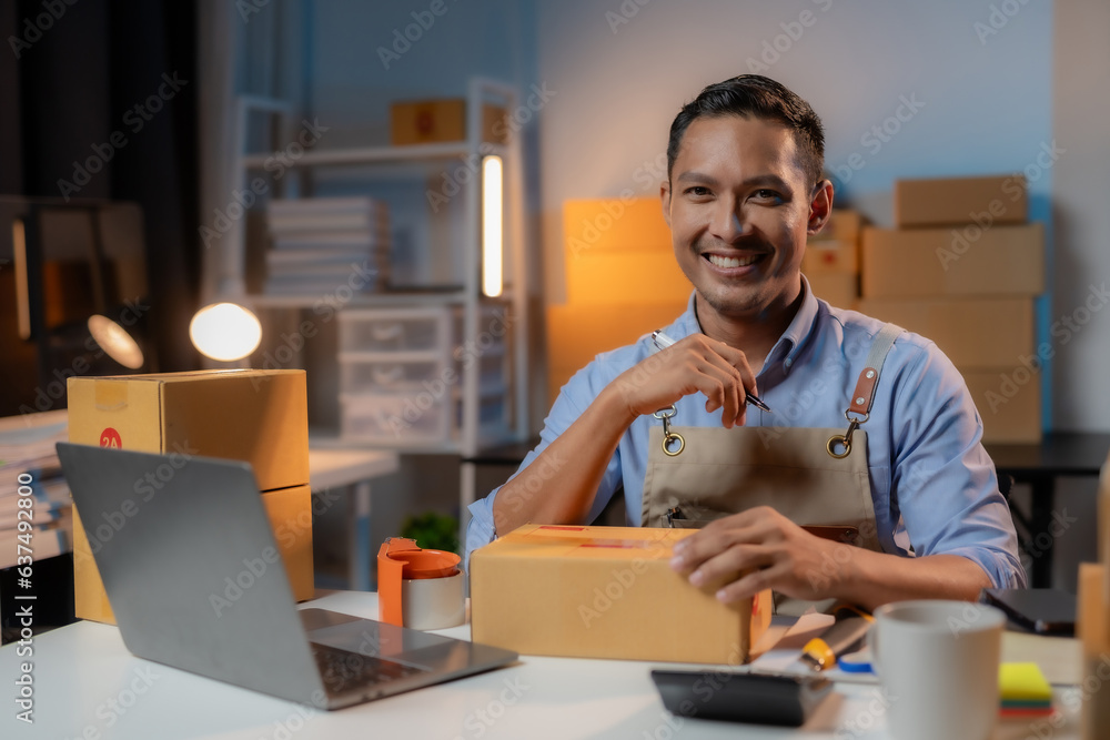 Asian man business owner selling online working overtime at night prepares to pack products and delivery according to customer address. Asian man business owner selling online working overtime at night prepares to pack products and delivery according to customer address.