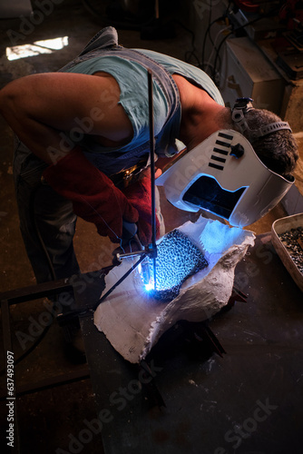 Craftsman in uniform in process of welding in garage