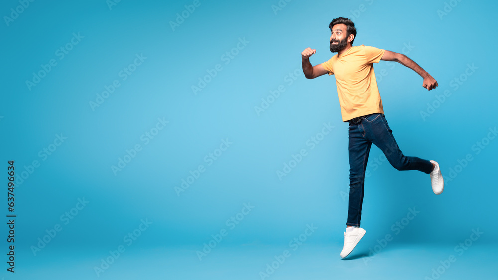 Funny middle aged indian man running, jumping in air, hurry up to sales or discounts, panorama, copy space Funny middle aged indian man running, jumping in air, hurry up to sales or discounts, panorama, copy space