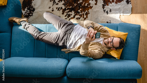 Fotografie top view man lying on sofa bed at home use mobile phone smart phone