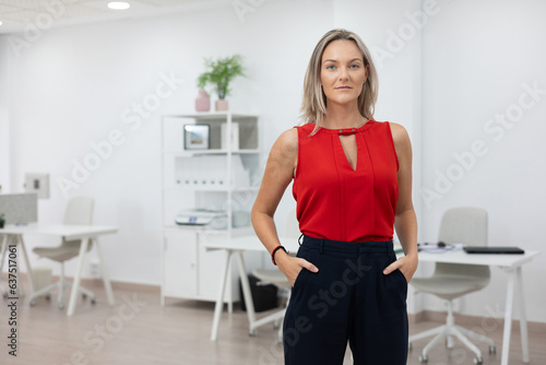 Portrait of beautiful executive woman in red blouse and office background.