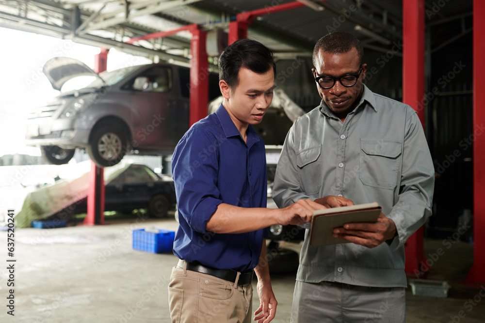 Fototapeta premium Car service worker explaining client what is wrong with his automobile