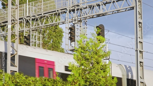 Passenger Commuter Train Passing under Railway Track Portal Catenary Support with Signal Devices Semaphores and Electric Power Lines