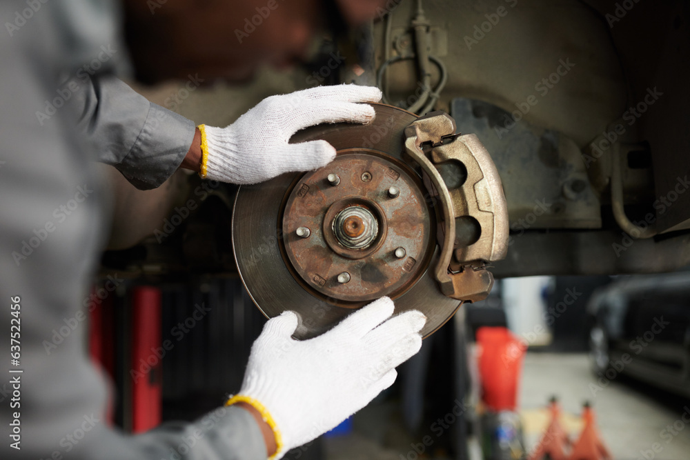 Closeup image of mechanic wearing textile gloves when checking car disc break