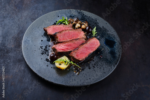Gourmet barbecue dry aged angus roast beef steak mini pear and mushrooms in amarena cherry sauce served as close-up in a Nordic design plate with copy space