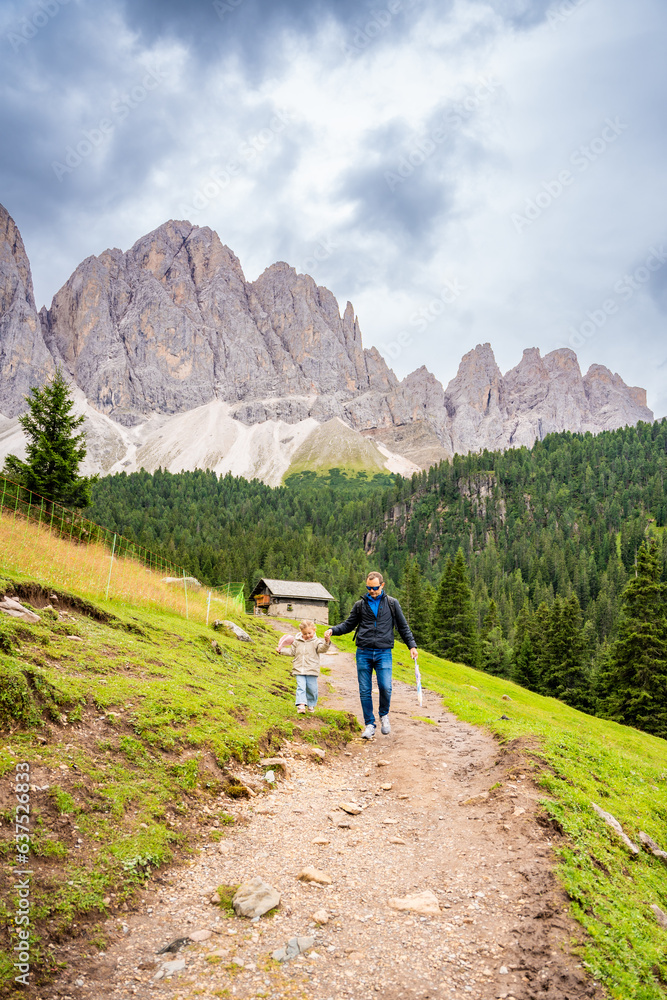 Tourists walking in alpine forest on summer day. Hikers traveler hikking with beautiful forest landscape, Dolomites, Italy