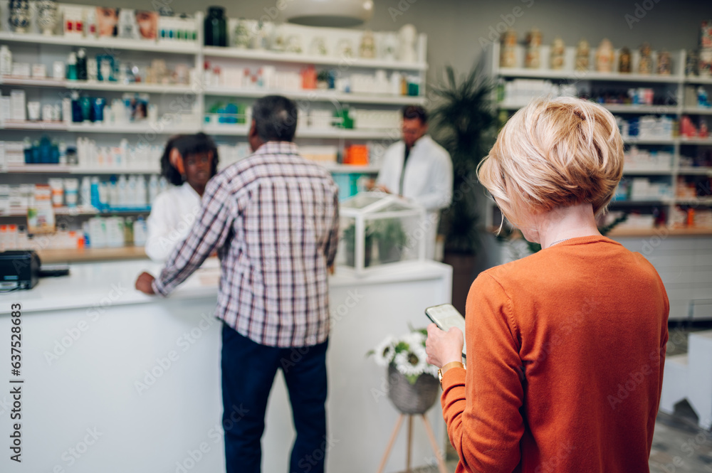 A queue of people standing in a pharmacy while shopping for medicine