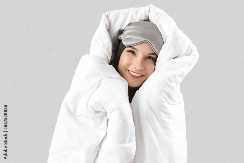 Beautiful happy young woman wrapped in soft blanket on grey background Beautiful happy young woman wrapped in soft blanket on grey background