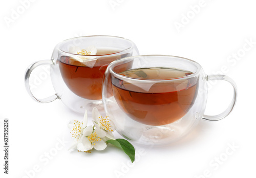 Glass cups of tea and beautiful jasmine flowers on white background
