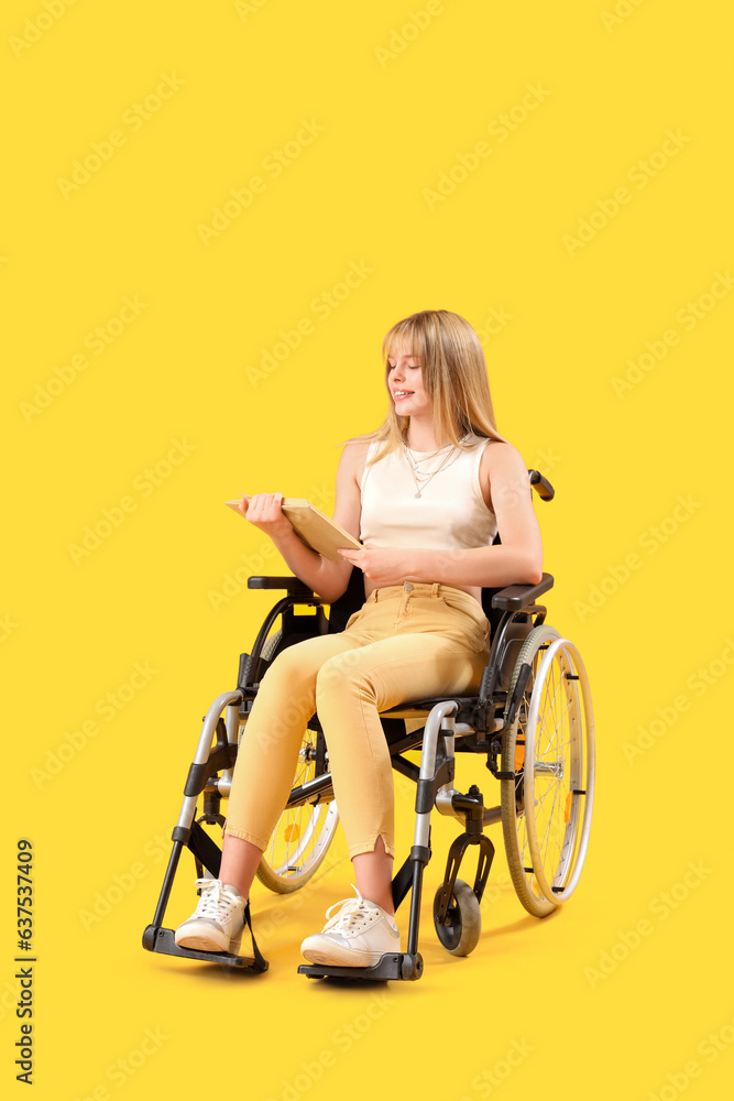 Young woman reading book in wheelchair on yellow background Young woman reading book in wheelchair on yellow background
