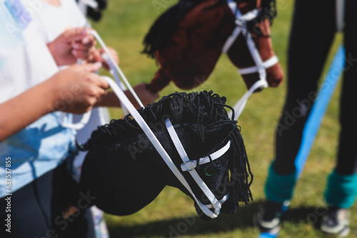 Fotografie Hobby horsing competition on a green grass, hobby horse riders jumping, equestri