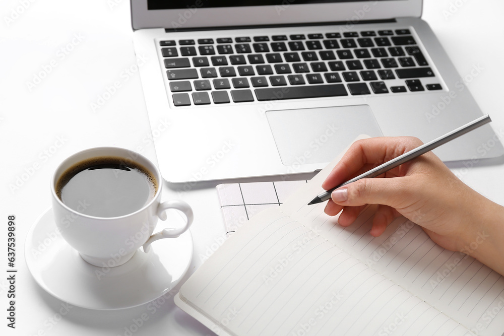 Female hand with pencil, notebook, cup of coffee and laptop on white background, closeup Female hand with pencil, notebook, cup of coffee and laptop on white background, closeup