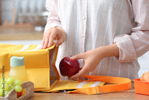 Fototapete Woman packing fresh meal into lunch box bag in kitchen