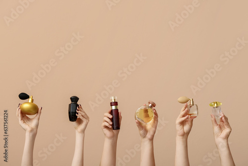 Foto Female hands holding different perfumes on beige background