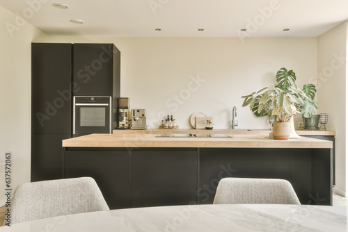 a modern kitchen with black cabinets and white marble countertops in the island is surrounded by a pot of plants