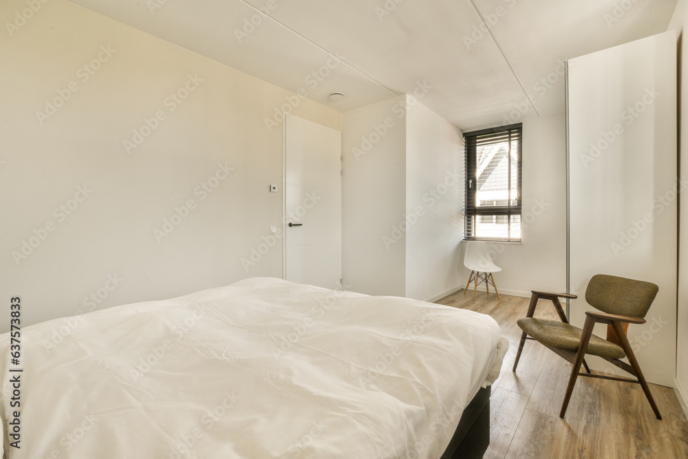 Fototapeta premium a bedroom with a bed, chair and mirror on the wall in it's corner window is visible to the room