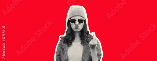 Portrait of bad girl expression showing hand with middle finger sign wearing colorful clothes, pink hat, sunglasses on red background, magazine style