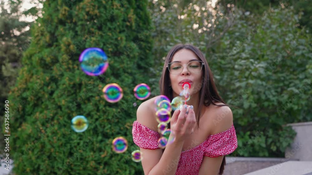 Beautiful Happy Woman Blowing Soap Bubbles on Street. Childhood in Adulthood. Smiling Face Optimistic Girl in Glasses Having Fun with Child toys. Funny Woman Playing Children's Game. Slow Motion. Beautiful Happy Woman Blowing Soap Bubbles on Street. Childhood in Adulthood. Smiling Face Optimistic Girl in Glasses Having Fun with Child toys. Funny Woman Playing Children's Game. Slow Motion.