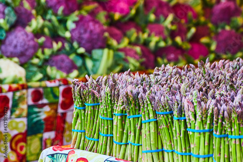Close up of asparagus on vegetable tablecloth with wall of purple cauliflower in background