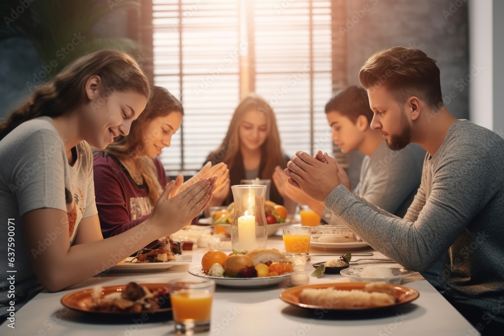 The family gathered around the table prays before eating.