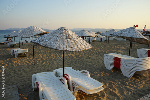 Große runde Sonnenschirme aus Korbgeflecht vor blauem Himmel im Licht der Abendsonne im Sommer am Strand von Sarimsakli bei Ayvalik in der Provinz Balikesir in der Türkei photo