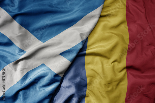 big waving national colorful flag of scotland and national flag of romania .