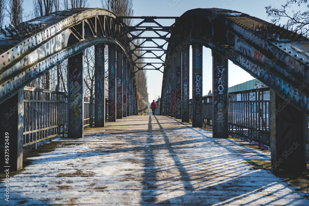 man walking over steel bridge in winter