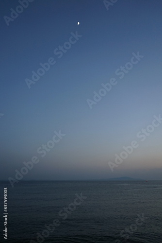 Blick vom Strand in Altinoluk im romantischen Licht der untergehenden Sonne auf den Golf von Edremit mit aufgehendem Mond am Ägäischen Meer in der Provinz Balikesir in der Türkei photo