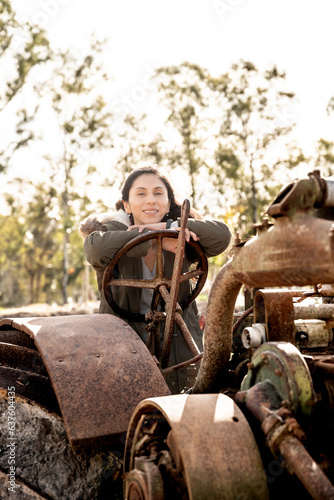 latin woman posing on old rusty tractor, on sunny afternoon © Juan