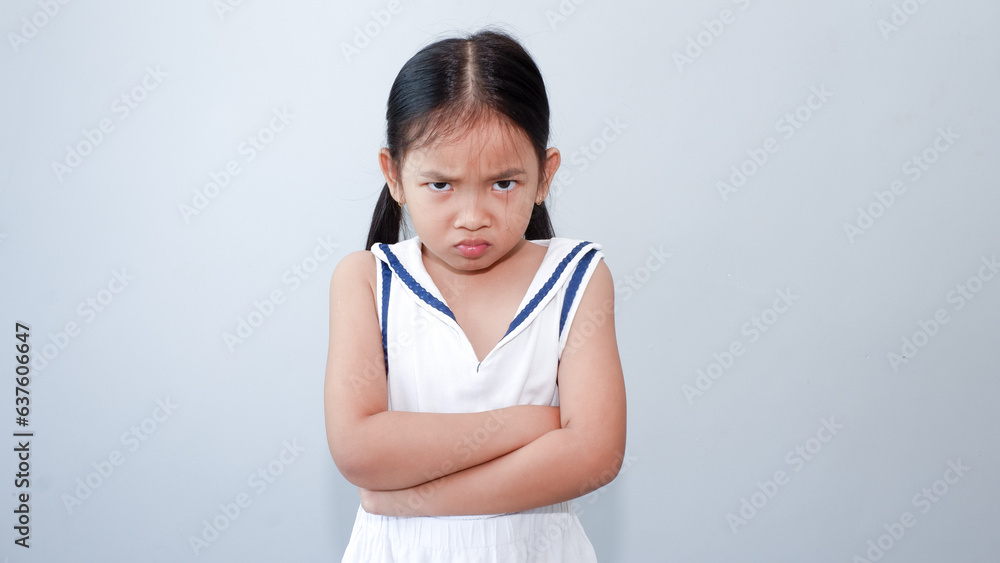 Portrait little girl with folded arms with dissatisfied grimacing face looking at camera Portrait little girl with folded arms with dissatisfied grimacing face looking at camera