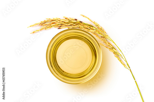 Glass bowl of rice bran oil extract with paddy on white . Top view photo