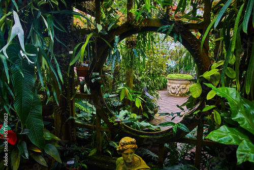 Macro of moon gate in trellis covered in plants with distant view of more plants photo