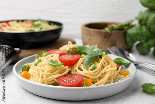 Delicious pasta primavera, ingredients and cutlery on light gray table, closeup