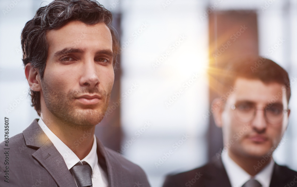 Two serious young businessmen standing with arms crossed in office Two serious young businessmen standing with arms crossed in office
