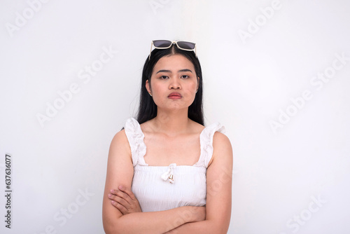 A grouchy young woman looking upset while crossing her arms. Looking at someone, maybe her boyfriend. Isolated on a white backdrop. © Mdv Edwards