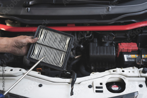 Auto mechanic cleaning an dirty engine air filters with air blow gun. photo