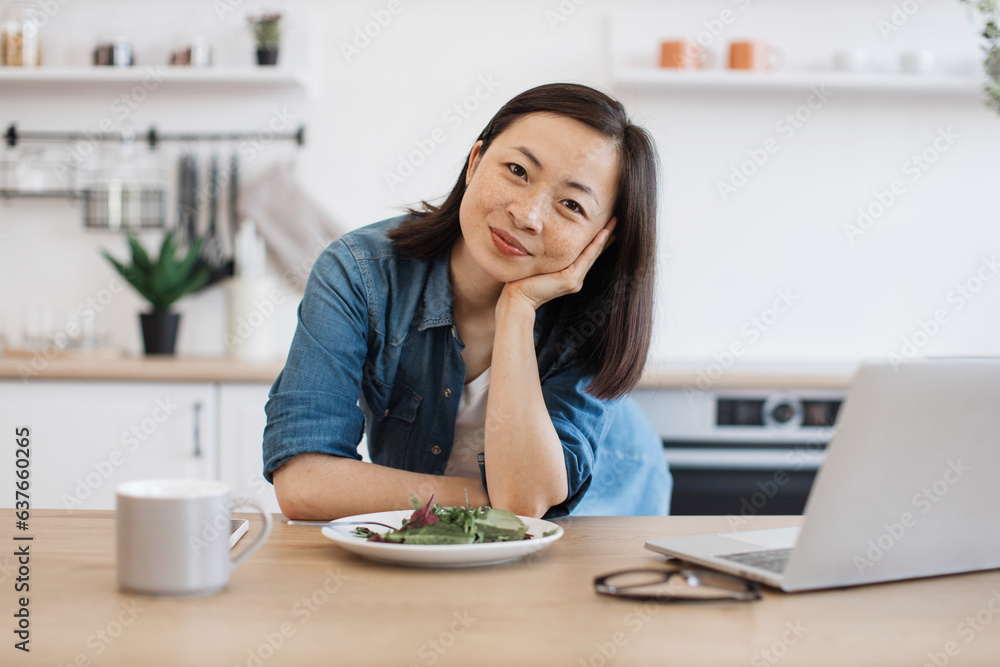 Remote employee sitting at table with laptop and salad Remote employee sitting at table with laptop and salad