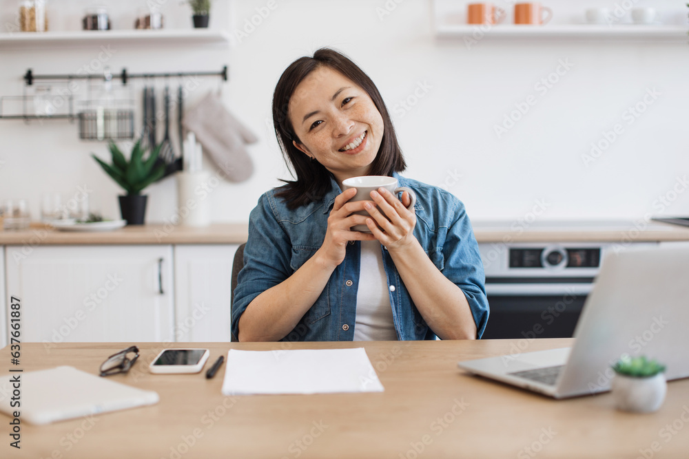 Young student sitting at kitchen table with mug in hands Young student sitting at kitchen table with mug in hands