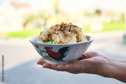 Hand supporting a bowl of chicken porridge from street vendor in Yogyakarta, 20 August 2023