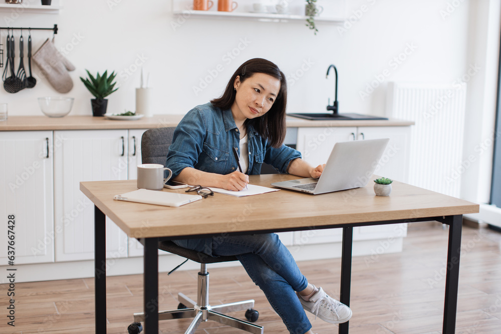 Busy woman surfing internet on computer at kitchen table Busy woman surfing internet on computer at kitchen table