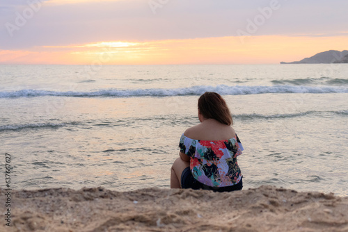 pensive latin woman in front of the sea at sunset