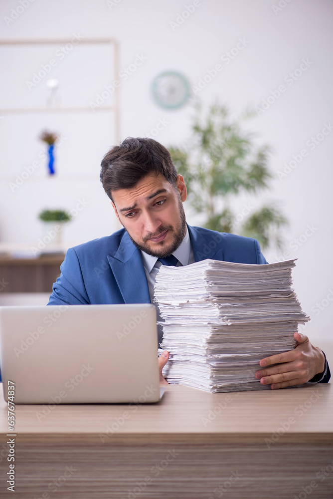 Young male employee and too much work in the office Young male employee and too much work in the office